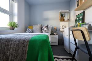 a bedroom with a bed with a green blanket and a chair at Roseland House in Falmouth