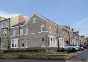 un gran edificio de ladrillo con coches estacionados frente a él en Apartment 5 Blue Bridge Court en York