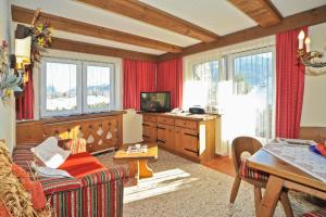 ein Wohnzimmer mit roten Vorhängen sowie einem Tisch und Stühlen in der Unterkunft Haus Salzburg in Seefeld in Tirol