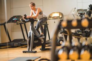 a woman riding an exercise bike in a gym at Apex City of Bath Hotel in Bath