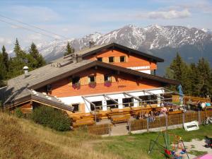 a large wooden building with people sitting outside of it at Panorama Restaurant Sterzingerhaus 1.930m in Vipiteno