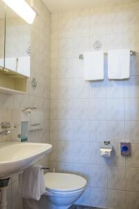 a white bathroom with a toilet and a sink at Gasthof Drei Eidgenossen in Bösingen