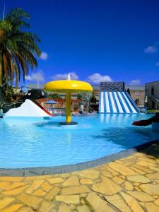 a large swimming pool with a yellow umbrella in the water at Pousada Clube Santa Cruz in Santa Cruz de Minas