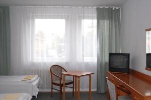 Cette chambre comprend un lit, une table et une télévision. dans l'établissement Krechowiak, à Augustów