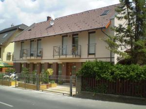 ein Haus mit einem Metalldach und einem Zaun in der Unterkunft Mary Apartmanház Hévíz in Hévíz