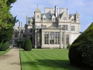 un grand château avec une pelouse devant lui dans l'établissement Stoke Rochford Hall, à Grantham