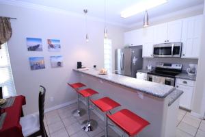 una cocina con barra y 4 taburetes rojos en Los Cabos III Condominiums, en South Padre Island