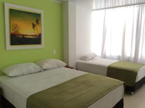 two beds in a room with green walls and a window at La Posada De Lulú in San Andrés