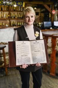 a woman is holding a menu in a store at Nashe Misto Guest House in Kovel