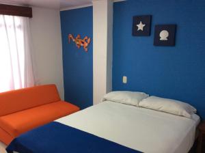um quarto com uma cama e uma cadeira laranja em La Posada De Lulú em San Andrés