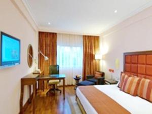 a hotel room with a bed and a desk at Parijatha Gateway in Bangalore