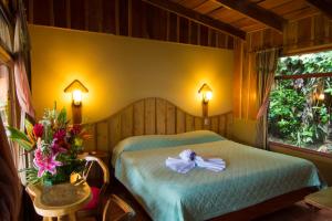 蒙特韋爾德哥斯達黎加的住宿－翠柏酒店，一间卧室,床上放着鲜花