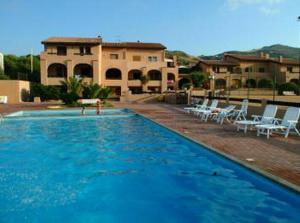 a large swimming pool with white chairs and a house at La Perla del Mare in Castelsardo