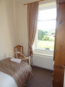 a bedroom with a bed and a large window at Fell Cottage in Keighley