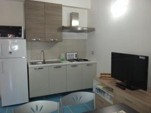 a kitchen with a white refrigerator and a tv at La Perla del Mare in Castelsardo