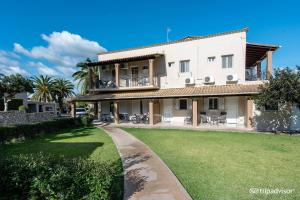 una grande casa bianca con un prato davanti di Anita a Perama