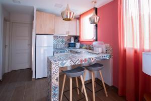 una cocina con paredes rojas y una barra con taburetes en Alhambra Boutique Apartments by TAM Resorts en Playa del Inglés