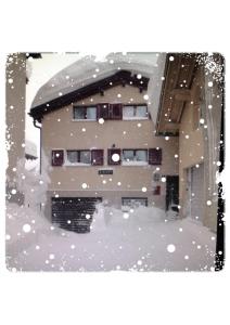 un edificio cubierto de nieve con un edificio en Privatzimmer / bed & breakfast, en Andermatt
