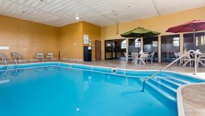 a swimming pool with an umbrella and tables and chairs at Best Western - Saluki Inn in Carbondale