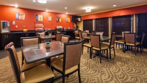 uma sala de jantar com mesas e cadeiras e paredes cor de laranja em Best Western - Saluki Inn em Carbondale