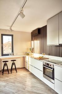 uma cozinha com armários brancos, uma mesa e uma janela em Forest Park by Zoom Apartments em Bratislava