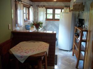 a kitchen with a table and a refrigerator at Chalés Vale Verde in Visconde De Maua