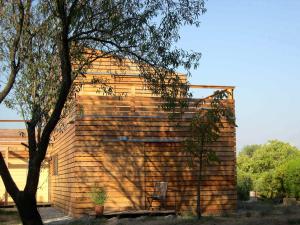 un edificio de madera con un árbol delante de él en Holzhaus, en Aix-en-Provence