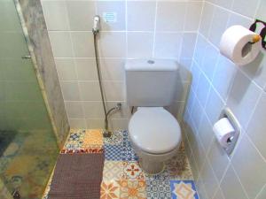a white toilet sitting next to a toilet paper roll at Pousada Pe da Serra in Tiradentes