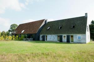 ein großes Haus mit einem Gamer-Dach auf einem Feld in der Unterkunft Gasterij Landschot in Hoogeloon