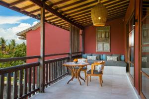 a balcony with a table and chairs and a couch at Amnaya Resort Kuta in Kuta