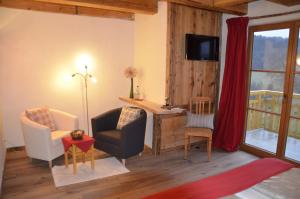 ein Wohnzimmer mit einem Stuhl und einem Schreibtisch mit einem TV in der Unterkunft Fehrenbacherhof Naturgästehaus in Lauterbach