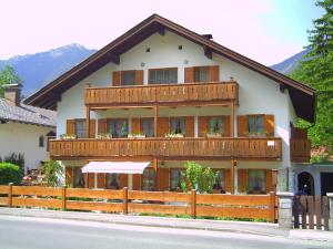 ein großes Gebäude mit Holzbalkonen und einem Zaun in der Unterkunft Ferienwohnungen Kral in Grainau