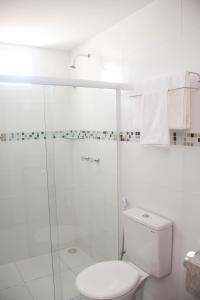 a white bathroom with a toilet and a shower at Hotel Executive in Delmiro Gouveia