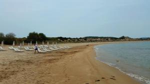 a person standing on a beach with chairs and the ocean at Romanos Beach Villas in Romanu