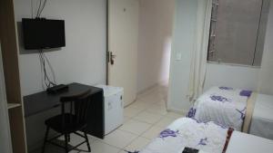 a small room with a bed and a desk and a television at Pousada Villa Branca - Petar (Apiaí-SP) in Apiaí