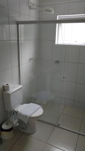 a white bathroom with a toilet and a shower at Pousada Villa Branca - Petar (Apiaí-SP) in Apiaí