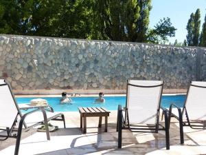 a group of chairs and a table in a swimming pool at Cabañas Monte Coiron in Malargüe