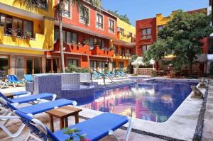a swimming pool with blue chairs next to a building at El Pueblito de Sayulita in Sayulita