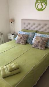 a bed with a green comforter and pillows on it at Toco el Cielo Aparts in Tigre