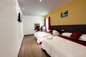 um quarto de hotel com três camas e uma parede em Myvilla Langkawi Hotel em Pantai Cenang