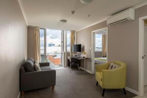 a living room with a couch and a chair and a desk at Quest On Ward Serviced Apartments in Hamilton