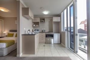 a small kitchen with a bed and a large window at Quest On Ward Serviced Apartments in Hamilton
