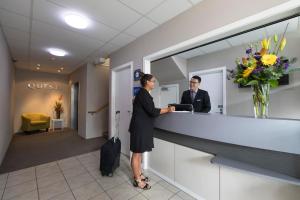 a woman standing at a reception desk in a lobby at Quest On Ward Serviced Apartments in Hamilton