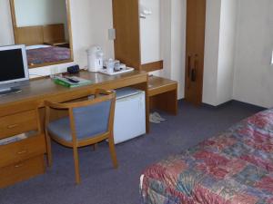 Zimmer mit einem Schreibtisch, einem Computer und einem Bett in der Unterkunft Hotel Kuki in Kuki