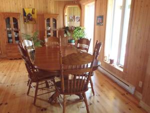 a dining room with a wooden table and chairs at Gîte La Maison Chez J.P. Bed and Breakfast in Havre aux Maisons