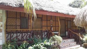 a small house with a thatched roof and stairs to it at Chelle's Guesthouse and Backpackers in Siquijor