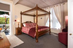 a bedroom with a canopy bed with a red bedspread at Sennen House Boutique Accommodation in Picton