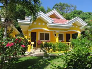 une maison jaune avec un jardin en face dans l'établissement Malapascua Garden Resort, à Malapascua