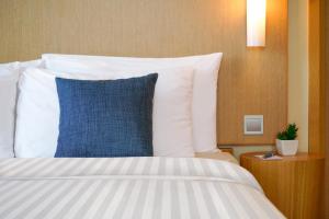 a bed with a blue pillow in a hotel room at Hotel COZi Harbour View in Hong Kong