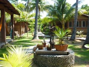 un patio con palmeras y una casa con macetas en Hotel & Bar La Guitarra en El Sunzal